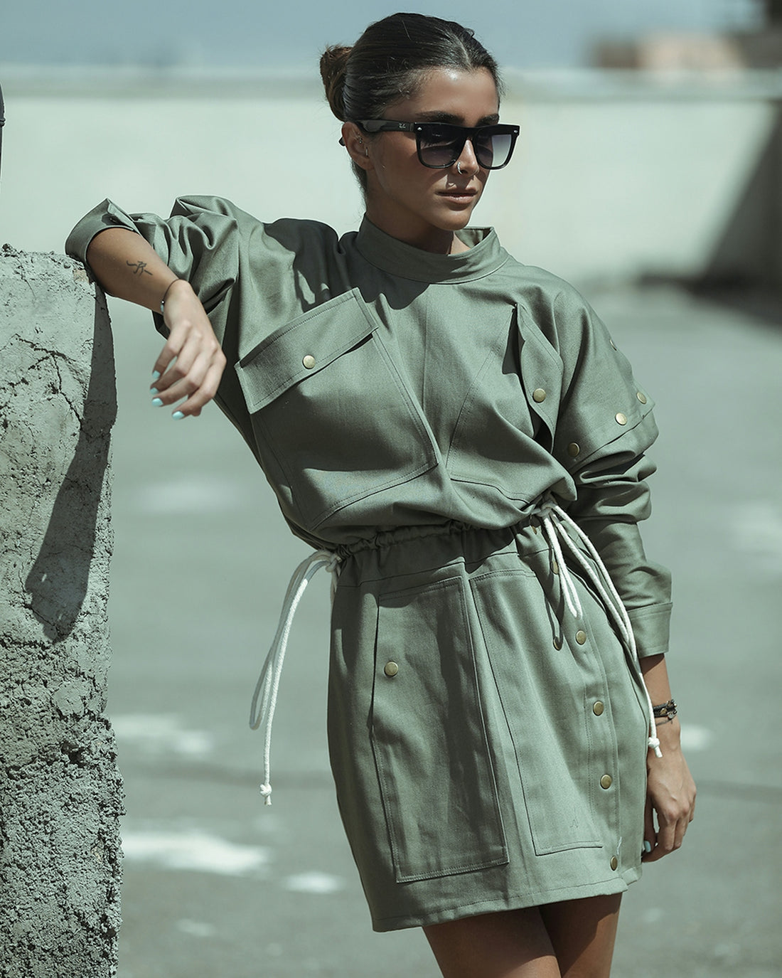 man in green button up shirt wearing black sunglasses standing beside body of water during daytime