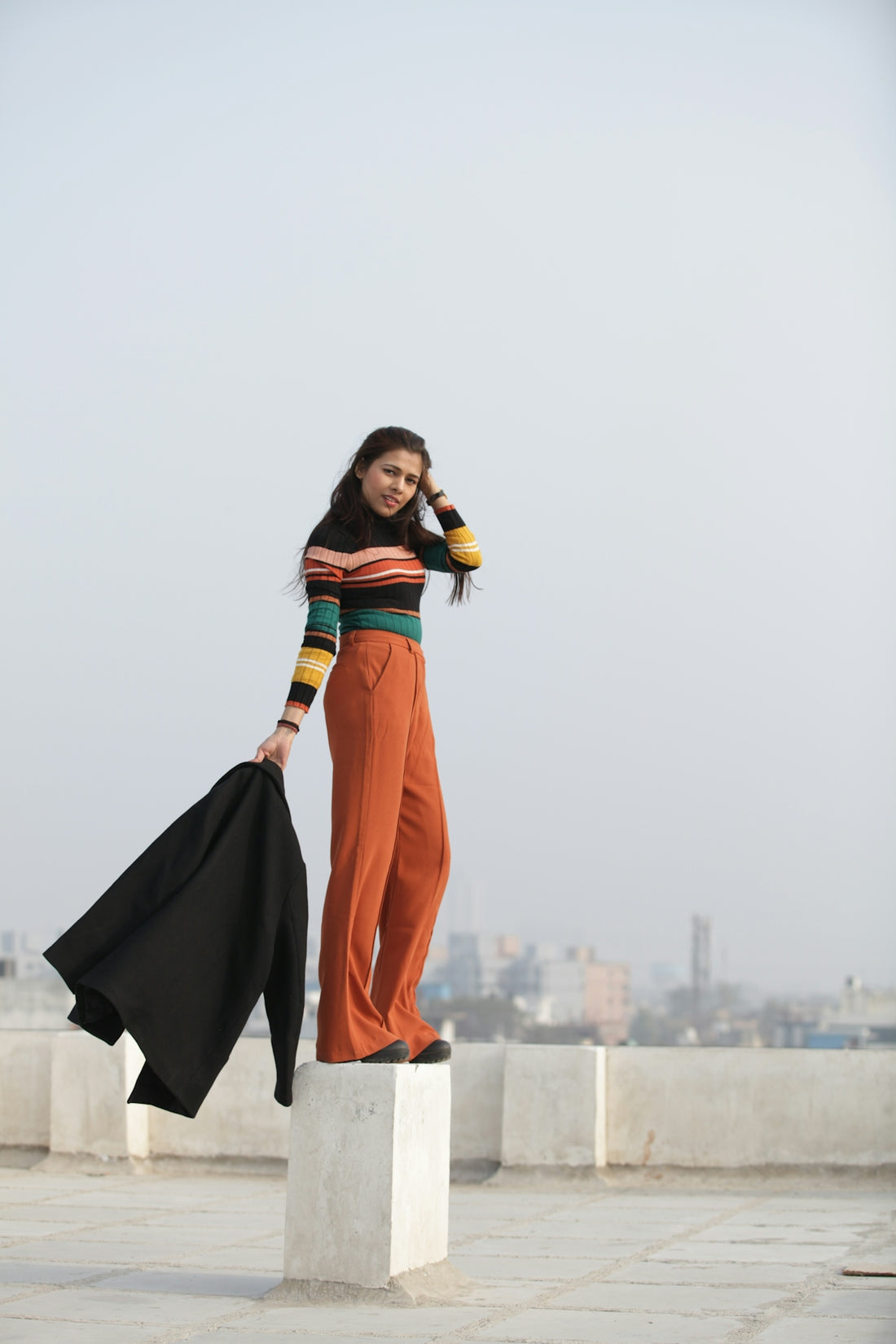 woman in black and orange dress standing on white concrete wall during daytime