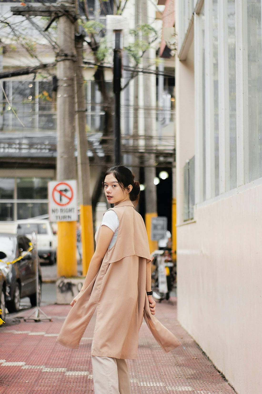 a woman walking down a street next to a tall building
