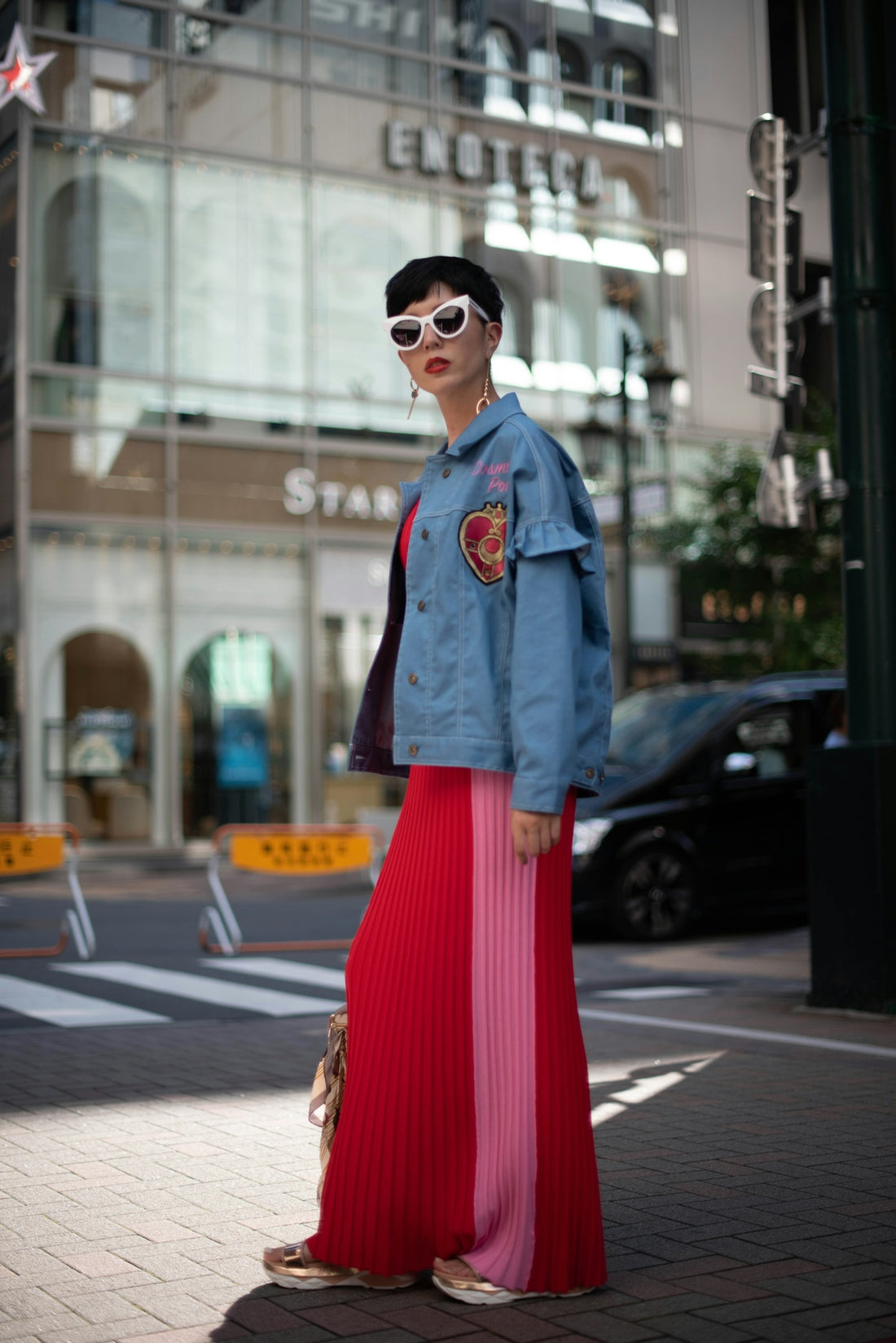 a woman in a red pleated skirt and denim jacket