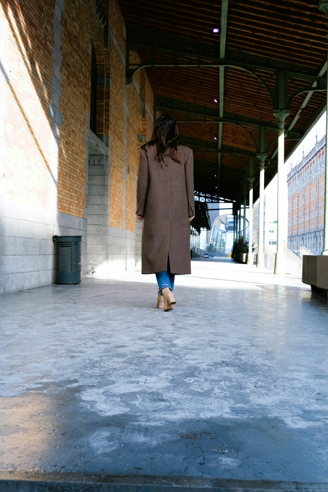 a woman walking down a walkway in a building