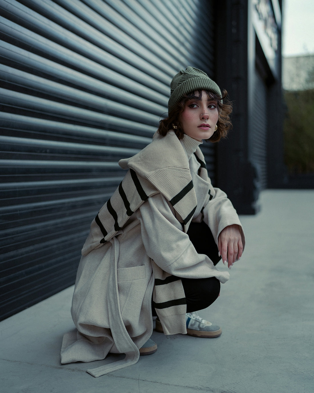 a woman in a trench coat leaning against a wall