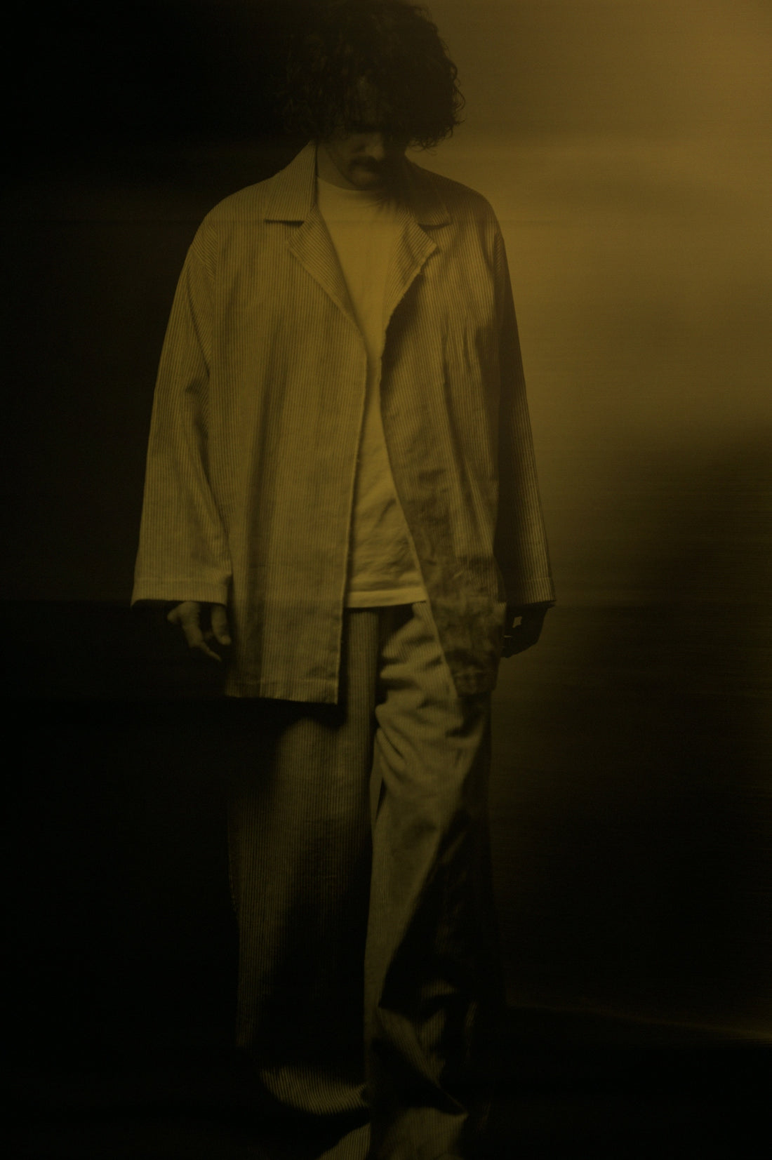 A man standing in a dark room with his hands in his pockets