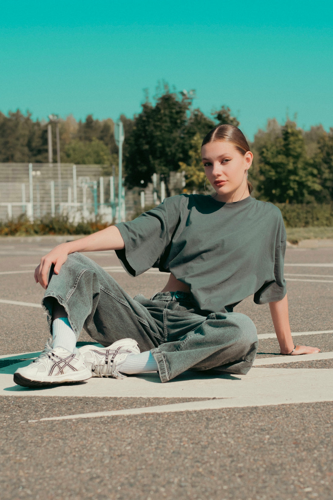 A girl sitting on the ground in a parking lot