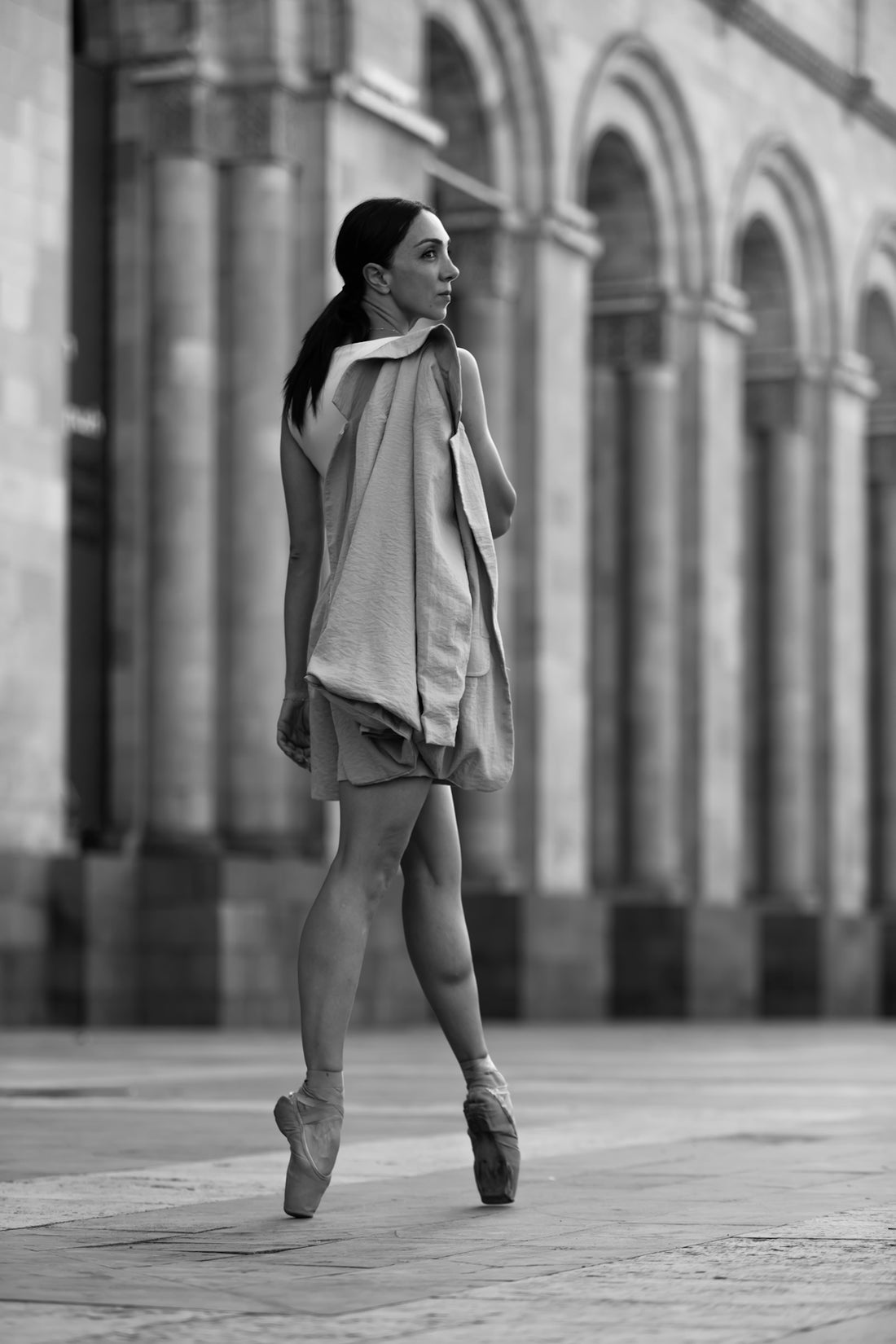 A woman walking down a street next to a tall building