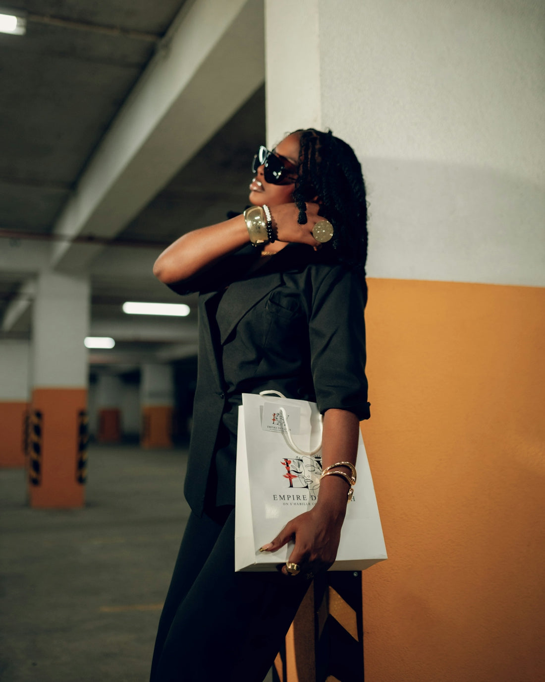 Woman in sunglasses holding a shopping bag in parking garage